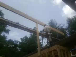 Carpenter setting a ridge beam over a new addition frame — Ice Dam Removal by Roofing Brothers in Nordland