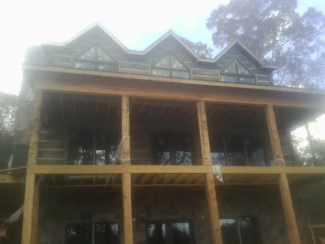 Dormers and porch framing on a large log home under construction — Roof Coating work by our crew in Nordland