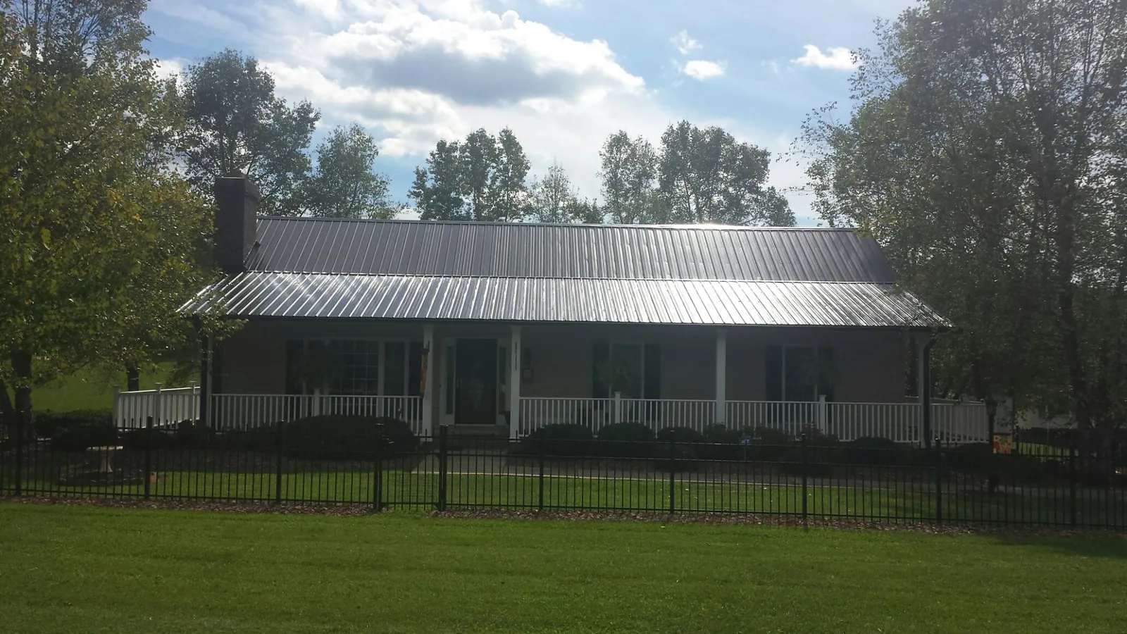 Gray metal roof on a brick ranch with a full width front porch — Gutter Guard Installation work by our crew in Nordland