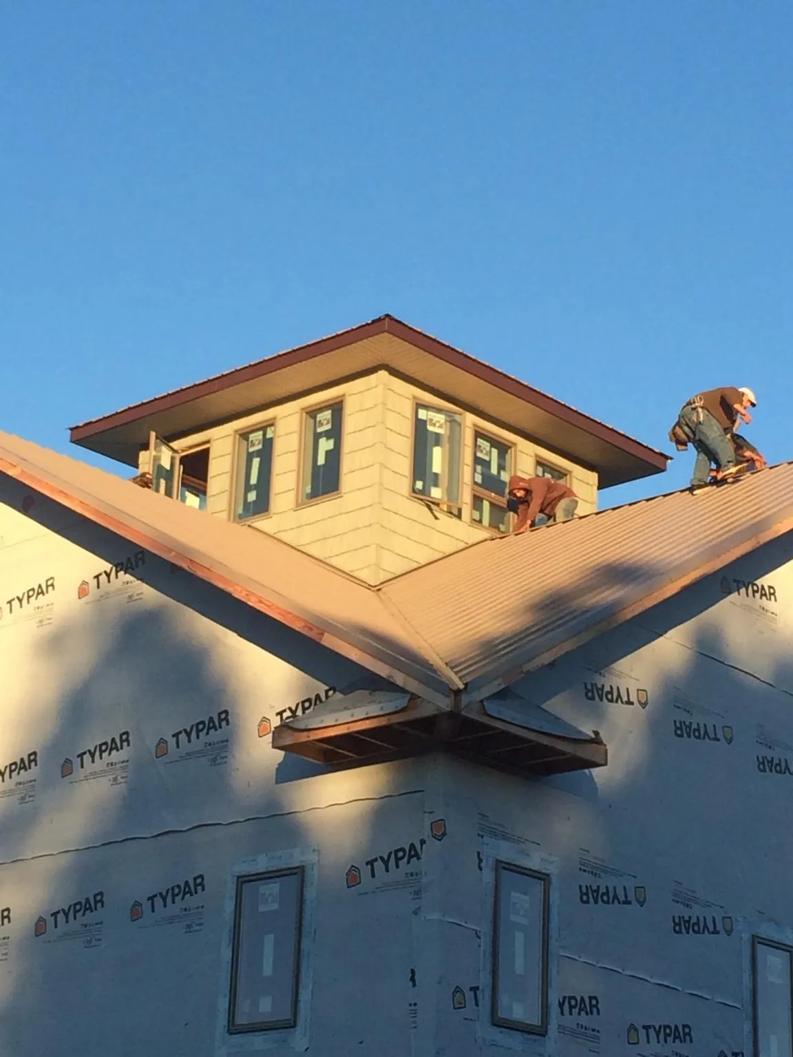 Roofers working around a rooftop cupola on a new metal roof at sunset — Roof Waterproofing in Nordland by Roofing Brothers